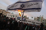 Hamas leader Mahmoud al-Zahar uses a torch to set fire to an Israeli flag reading in Arabic 