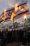 Hamas leader Mahmoud al-Zahar uses a torch to set fire to an Israeli flag reading in Arabic 
